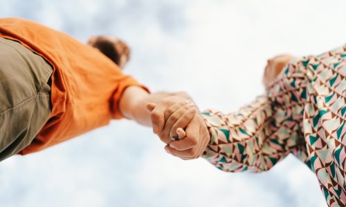 Happy young couple in colorful clothes with sky on background